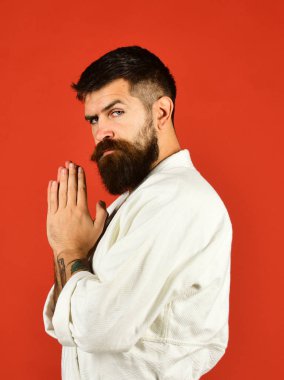 Kırmızı arka planda beyaz kimonolu sakallı adam.