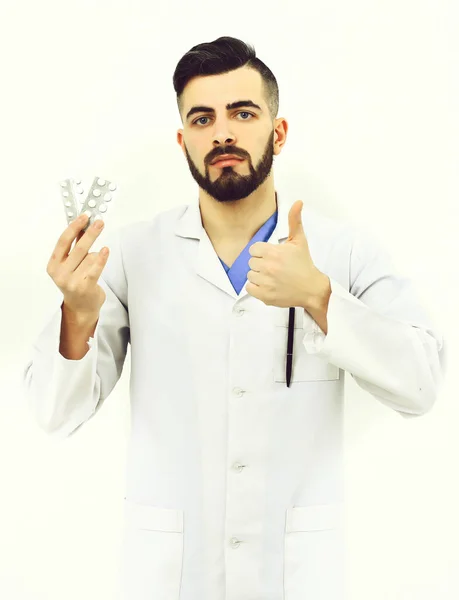 Doctor with stylish haircut and beard holds pills in hand — Stock Photo, Image