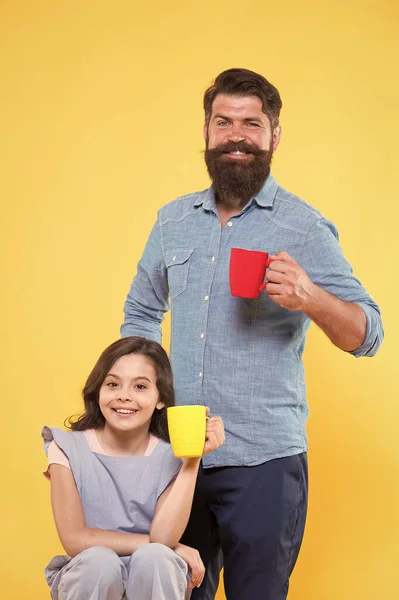 Padre e hija beben té en casa. Concepto de fiesta de té. Buenos días. Tomando café juntos. Equilibrio hídrico y salud. Té familiar. Barbudo hombre y feliz niña sosteniendo tazas — Foto de Stock