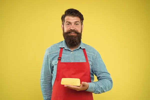 Is onder controle. Een gelukkige man met een baard houdt kaas. kaasbereidingstechnieken. kaasmaker. hipster met baard in schort. Zuivelwinkel. Online winkelen. Gourmetproduct — Stockfoto