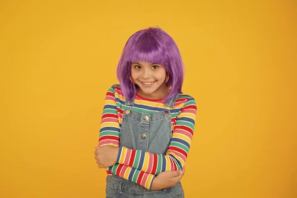 Uwielbiam zmieniać fryzurę. Słodki uśmiech małej dziewczynki z fantazyjnymi włosami. Szczęśliwe małe dziecko nosić krótkie peruki włosów. Zabawny dzieciak z fioletowymi syntetycznymi włosami. Piękno i moda — Zdjęcie stockowe