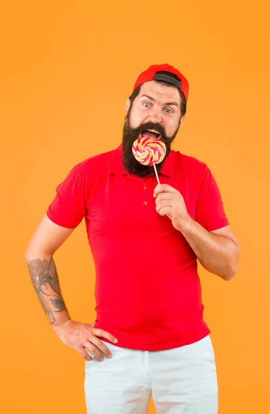 Man eat big colorful lollipop. happy hipster love sweet food. diet and calorie. Man with lollipop and smile. brutal bearded man in uniform. care about healthy smile. sweet taste