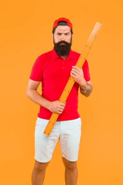 Brutal trabajador de servicio con gobernante. medir la longitud. Midiendo una línea. de vuelta a la escuela. Profesor mantenga regla métrica fondo amarillo. hombre barbudo preparándose para las matemáticas y la lección de geometría — Foto de Stock