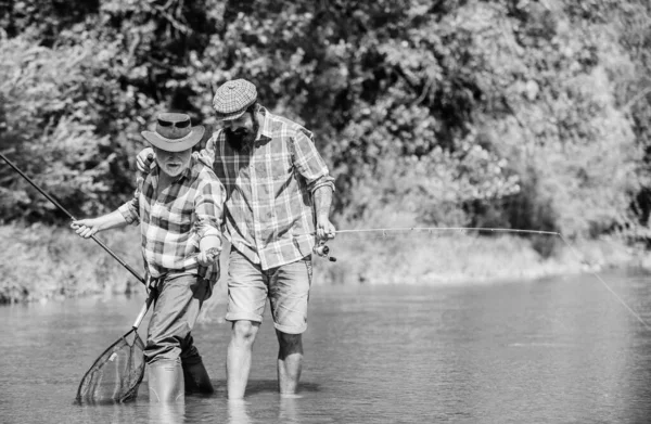 Padre e figlio pescano. Bella presa. Asta e placcaggio. Attrezzatura da pesca dei pescatori. Pescatore nonno e maturi amici uomini. Famiglia di pescatori. Hobby attività sportive. Weekend estivo. Attività pacifica — Foto Stock