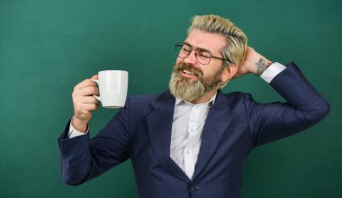 Sakin ol ve mola ver. Sakallı adam kahve fincanı tutuyor. Okul tatilinin tadını çıkarıyorum. Mutlu öğretmen kahve molasının tadını çıkar. Mola zamanı. Sabah ve kahvaltı. Dinleniyor ve dinleniyor. Kahve beyin fonksiyonlarını güçlendirir.