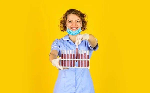 Ερευνητής εργαστηρίου. Η γυναίκα φοράει προστατευτική μάσκα. Κάνοντας εργαστηριακό πείραμα. Εξέτασε το αίμα σου. επιστήμονας με μάσκα προσώπου και γάντια που κρατά δοκιμαστικό σωλήνα με κόκκινη ουσία. Δοκιμαστικοί σωλήνες ελέγχου διερευνητών — Φωτογραφία Αρχείου