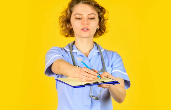 Administração do hospital feminino em um centro médico moderno. enfermeira em casaco médico com documentos escreve informações importantes. enfermeira escrevendo alguns dados na pasta de papéis. foco seletivo — Fotografia de Stock