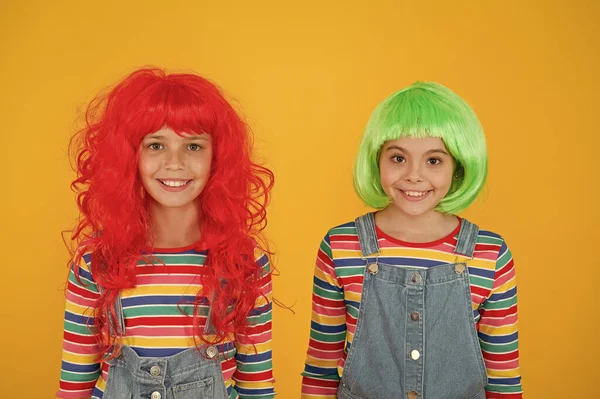 Moda y artística. Los niños felices usan pelucas de pelo de moda de fondo amarillo. Las niñas sonríen con aspecto de moda. Peluquería de moda. Moda y estilo —  Fotos de Stock