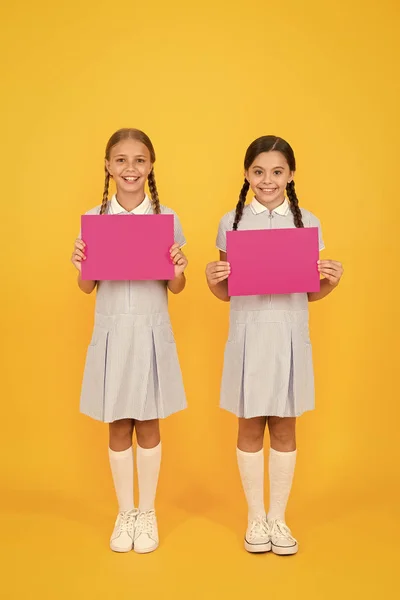 Promoting product. Read this. Upcoming event. Girls tidy dress hold poster. Schoolgirls hold poster copy space. News information. Changes coming. Back to school concept. Schoolgirl pupil show poster — Stock Photo, Image