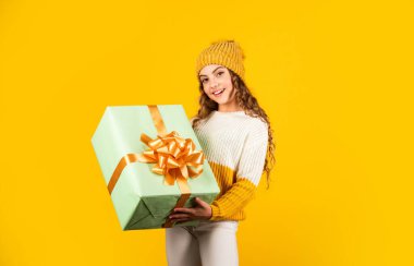 Satın alma ve teslimat. Alışveriş merkezi. Doğum günü kızı. İyi tatiller. Xmas hediye alışverişi. Hediye paketi. Tatlı rüyalar. Boks günü. Genç kız hediye kutusunu tutuyor. Çocuk mevcut kutuyu sarı arkaplanda tut