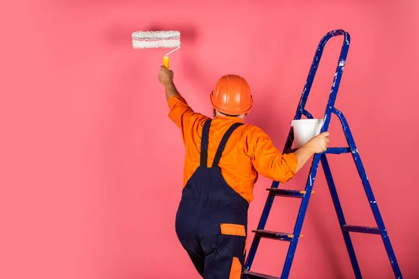 Il adore son boulot. faisant outil de réparation. Peintre travaillant sur chantier. senior utiliser rouleau sur échelle. travailler dans l'appartement. Artisanat avec rouleau de peinture. Maison Peinture et rénovation des affaires — Photo