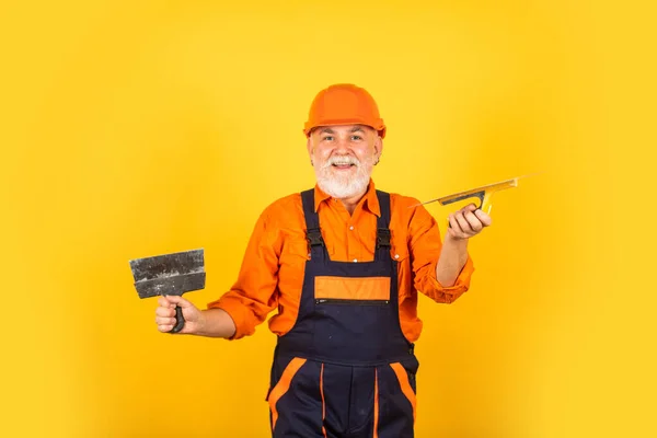 Arbeit für echte Männer. Putzwerkzeuge für Putz. Gipskellen-Spachtel auf gelbem Gipskarton. Gipser in Arbeitsuniform. Mann mit Spachtel. Prozess des Auftragens von Spachtelmasse — Stockfoto