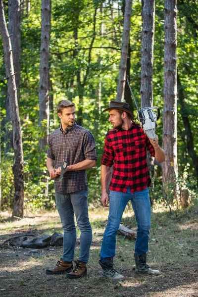 rangers use lumberjack equipment. Lumberjack with chainsaw and ax. Harvest firewood. hiking in wood. forest care at vacation. summer or spring activity. man farmers relax in forest. summer vacation