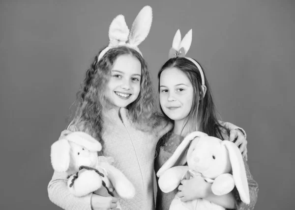 Sisters smiling cute bunny costumes. Spread joy and happiness around. Hope love and joyful living. Friends little girls with bunny ears celebrate Easter. Children with bunny toys on blue background — Stock Photo, Image