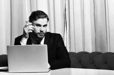 Sakallı adam, elinde bir bardak viski tutan iş adamı dizüstü bilgisayarda çalışıyor.