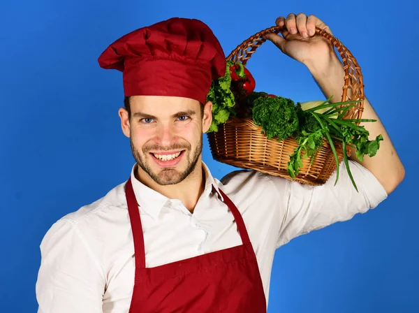 Cook with cheerful face holds wicker basket of fresh veggies. — Stock Photo, Image