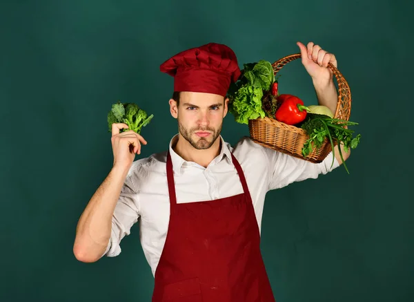 Chef em uniforme de Borgonha com brócolis e cesta de legumes . — Fotografia de Stock