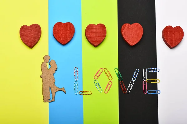 Pinzas de papel de colores que forman la palabra AMOR y corazones de madera — Foto de Stock