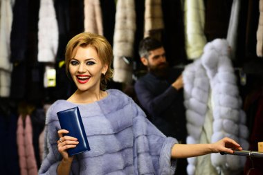 Bayan pahalı kürk mantolarını deniyor. Erkek ve kız.