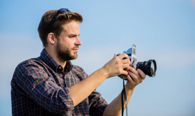 Adam açık havada gökyüzü arka planında. Antika ekipmanlar. Blogger video blogu çekiyor. Tatil zamanı. Yakışıklı blogcu, gezgin, geçmişe dönük kamera. Fotomuhabir konsepti. Gezgin blogcu. Gazeteci fotoğraf çekiyor.