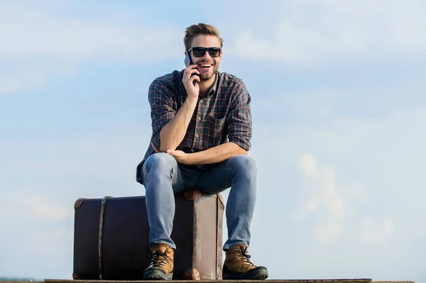 Pak het moment. macho man toerist ontspannen tour tas. sexy man hemel achtergrond spreken over de telefoon. Mannenmode. Ziet er zo trendy uit. Reiziger wacht op taxi. Aan de kant. Zakenman met bril. zakenreis — Stockfoto