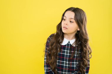 Saf güzellik. Küçük güzel, uzun kıvırcık saçlı. Çocuklar için şık okul üniforması. Sağlıklı saçların güzelliği. kopyalama alanı. Küçük model sarı arka plan. Saçları mükemmel. Mutlu Çocuklar Günü