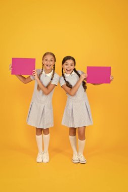 Retro üniformalı mutlu arkadaşlar. Klasik çocuk modası. Okula dönüyorum. Küçük kızlar boş kağıt tutarlar. Çocuklar için ansiklopedi kitabı. Küçük kızlar edebiyatı sever. Eski usul. Duyuru. Boşluğu kopyala.