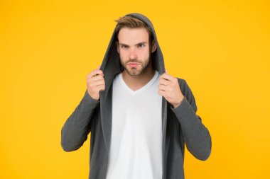 Esneme malzemesi. Yakışıklı adam kapüşonlu şık bir manto giyiyor. Sıradan erkek giyimi. Moda trendleri. Gençler için modern kıyafetler. Günlük yaşam için rahat kıyafetler. Moda adamı sarı arka plan. Moda bakışı.