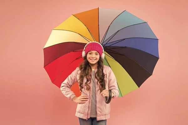 La lluvia es mi música favorita. Niño pequeño feliz con paraguas de color arco iris para el paseo de otoño. Niño sonriendo con paraguas para el clima lluvioso de otoño. Accesorio de otoño de moda. Temporada de otoño — Foto de Stock