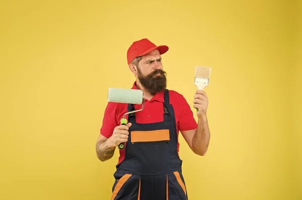 Pick-Ups. Malwerkzeug. Pinselwalzenmaler. Mann bärtige Arbeiter Malerei. Reparatur und Renovierung. Bauarbeiter halten Farbroller und Pinsel in der Hand. perfekte Oberflächenbemalung. Emulsionsfarbe — Stockfoto