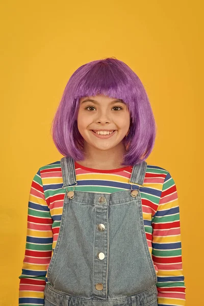 Ser uma criança chique. Criança pequena usar cabelo violeta peruca fundo amarelo. Criança feliz com penteado curto reto em estilo casual. Bonito pequeno sorriso criança com aparência de moda — Fotografia de Stock