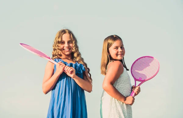 Bambini energici. felice e allegro. gioco sportivo gioco. Giochi estivi all'aperto. giocare a tennis. felicità infantile e sorellanza. bambine con racchetta da tennis. attività sportiva estiva — Foto Stock