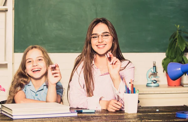 Hulp met huiswerk. Huiswerk project. Zuster helpt met leren. Leraar vriendelijke dame met leerling. Huiswerk maken met mama. Kleine meid en vrouw zitten aan het bureau. Schoolonderwijs. Samen studeren — Stockfoto