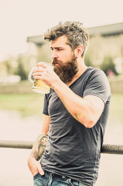 Homme avec barbe et moustache tenir verre de bière à l'extérieur. Le type se repose avec de la bière fraîche. Hipster détendue boire de la bière en plein air. Café terrasse d'été. Bières légères ou stouts sombres les boivent toutes — Photo