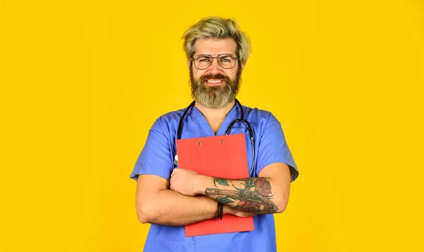 De buen humor. Médico profesional sosteniendo carpeta. enfermera barbuda madura sosteniendo portapapeles. médico masculino usa estetoscopio. terapeuta en uniforme en el hospital. historia clínica y prescripción — Foto de Stock