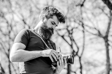 Elle ayarlar. Sakallı ve bıyıklı bir fotoğrafçı. Adam fotoğraf çekiyor. İçerik yaratan. Sakallı hippi fotoğrafçı. Eski ama yine de iyi. Fotoğrafçı klasik fotoğraf makinesini tutar. Modern blog yazarı