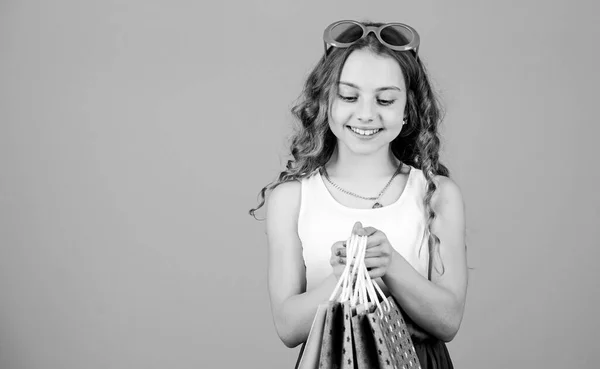 Marque préférée des enfants. Fille avec sac à provisions. Visite de shopping à l'étranger. Vente de saison estivale. Achats et achats. Vendredi noir. Rabais de vente. Journée shopping. Enfant de la mode fille lunettes de soleil tenir paquet — Photo