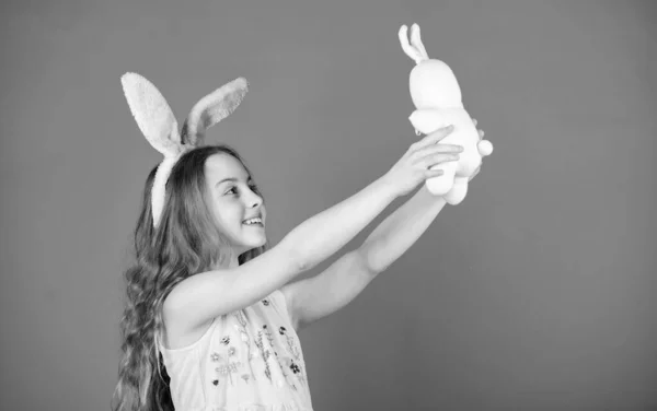 イースターの日に再生します。イースター グッズとウサギの耳を着ている小さな女の子。おもちゃで遊んでイースターのウサギのスタイルで、幼い子供。かわいいおもちゃの小さな子。イースターのウサギ。小さな女の子とウサギのおもちゃ — ストック写真