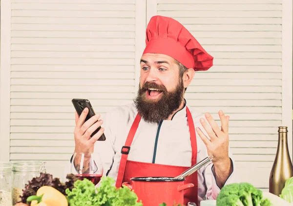 Culinary education online. Elearning concept. Man chef searching internet recipe cooking food. Chef smartphone watch culinary show. Culinary school. Hipster in hat and apron learning how cook online