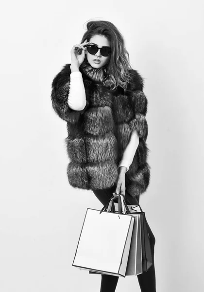 Lady hold shopping bags. Discount and sale. Buy with discount on black friday. Shopping or birthday gift. Woman shopping luxury boutique. Girl wear sunglasses and furry coat shopping white background — Stock Photo, Image