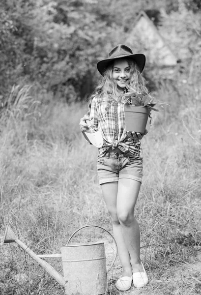 Planting plants. Little kid hold flower pot. Spring country works. Happy childrens day. Happy childhood. Child in hat with shoulder blade small shovel hoe. Happy smiling gardener girl. Ranch girl