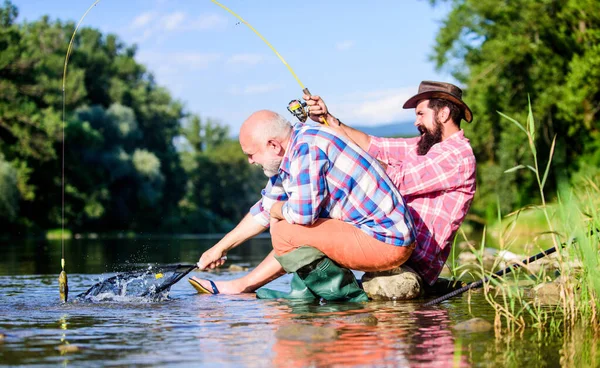 Men sit at riverside with fishing equipment. Poaching crime and fishing license. Poachers fishing. Black market caviar. Illegal hunting caviar. Extracts eggs from sturgeon caught river. Trap for fish — Stock Photo, Image