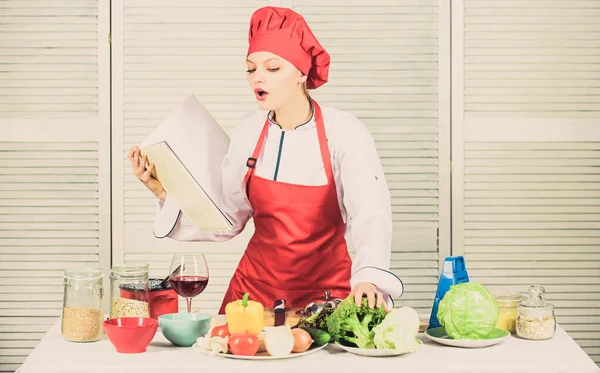 Βοηθητικό βιβλίο μαγειρικής. Γυναίκα σεφ μαγειρεύει. Μαγειρική έννοια. Ερασιτέχνης μάγειρας διαβάζει συνταγές βιβλίων. Κορίτσι μαθαίνουν συνταγή. Βιβλίο του διάσημου σεφ. Βελτιώστε την ικανότητα μαγειρικής. Συνταγές βιβλίων. Σύμφωνα με τη συνταγή — Φωτογραφία Αρχείου