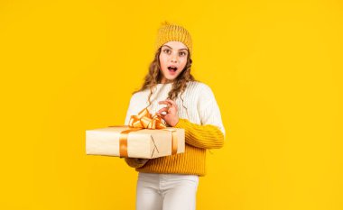 Alışveriş hediyesinden sonra şık bir genç kız. Küçük çocuğun elinde kutu sarısı arka plan var. Alınan paket. Alışveriş yapmak mükemmel bir hediye bulmaktır. Şirin çocuk alışverişi seviyor. Hediye paketi olan alışveriş bağımlısı.