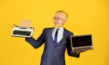 Dizüstü bilgisayara karşı daktilo. İş adamı modern teknolojiyi kullanır. Adam sakalını sarıya boyamış. Yeni modern aletler al. Yararlı bir cihaz. Modern yerine modası geçmiş. Vintage değerleri uzmanı