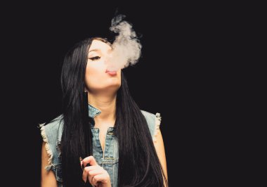 Kız buharı. Göz kamaştırıcı esmer sigara içen siyah arka plan. Dinlen ve rahatla. Nargile barı. Elektronik sigara. Moda kızı vapuru. Beyaz duman bulutu. Vapur kullanmak seksidir. Nikotin bağımlılığı