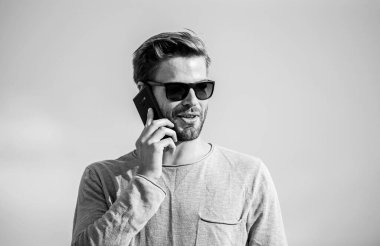 Başvuru ve internet. Hippi güneş gözlüğü takıyor cep telefonuyla gökyüzü arka planı tutuyor. Hippi akıllı telefon görüşmesi. Önemli bir cep telefonu sohbeti. Adam cep telefonu. İrtibatı koparmayalım. Mobil çağrı kavramı