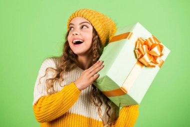 Çocuk hediye kutusunu tut. İyi tatiller. Neşeli küçük kız örgü şapka ve kazak örüyor. Doğum günü sürprizi. Alışveriş merkezi konsepti. Doğum günü kutlaması fikri. Keyfin yerinde. Doğum günü geleneği