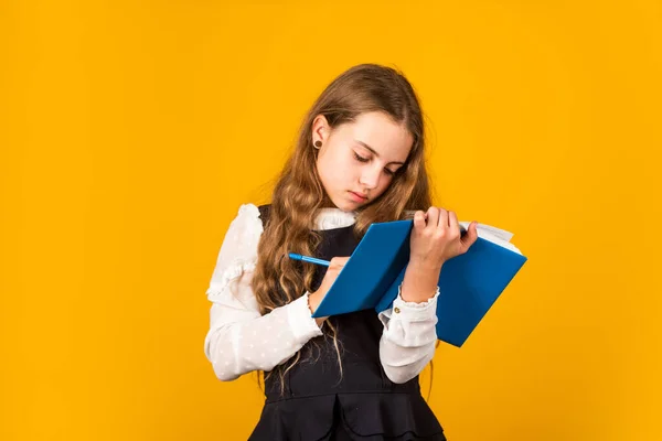 Estudia hoy. Un niño pequeño escribe en un libro de estudio. Una niña pequeña hace registros de estudio. Escuela y educación. Clases privadas. Mejorar sus habilidades de estudio, espacio de copia — Foto de Stock