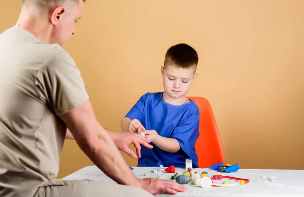 El pequeño doctor se sienta en la mesa de herramientas médicas. Salud. Concepto de pediatra. Examen médico. Niño lindo niño y su padre médico. Trabajador del hospital. Servicio médico. Laboratorio de análisis — Foto de Stock